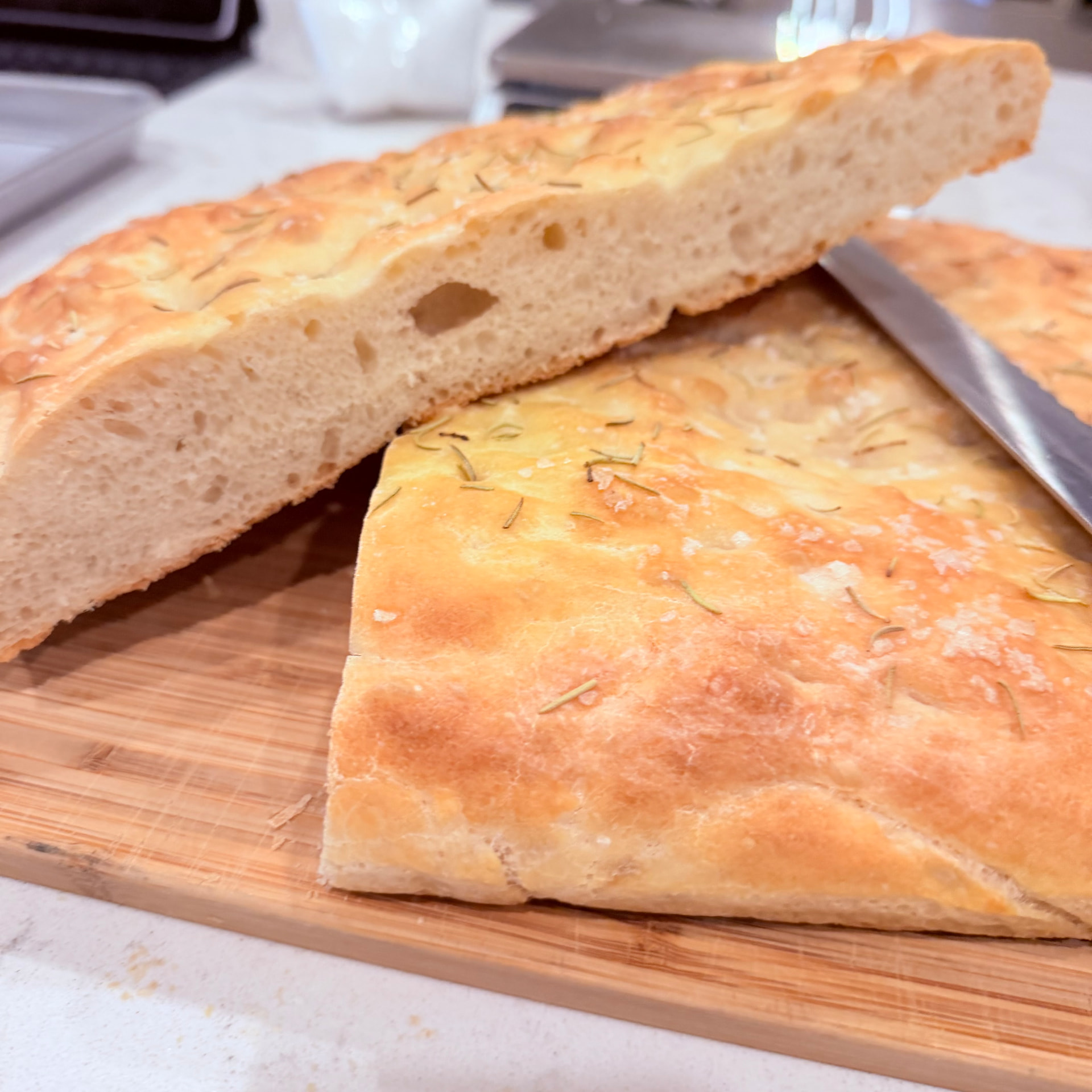Golden olive-oil focaccia with rosemary and sea salt on a wooden board — Mama Rozi's Bakehouse in LaGrange, KY
