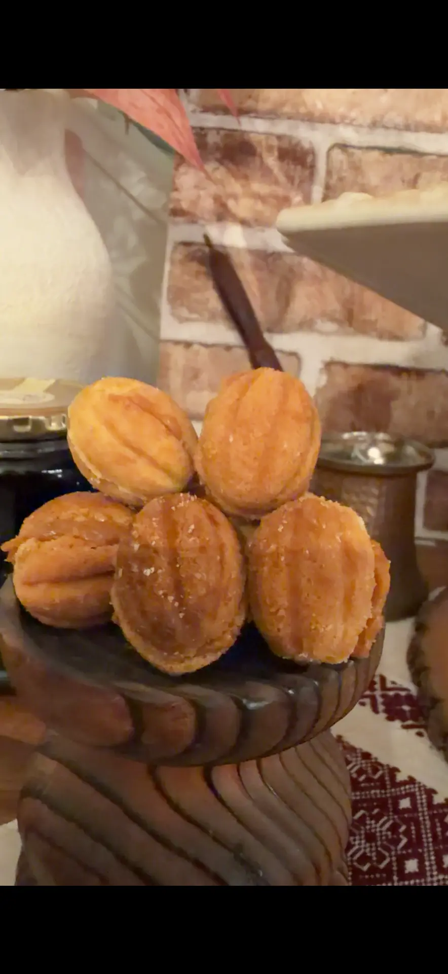 Golden walnut-shaped cookies filled with dulce de leche walnut filling on a pedestal — Mama Rozi's Bakehouse in LaGrange, KY