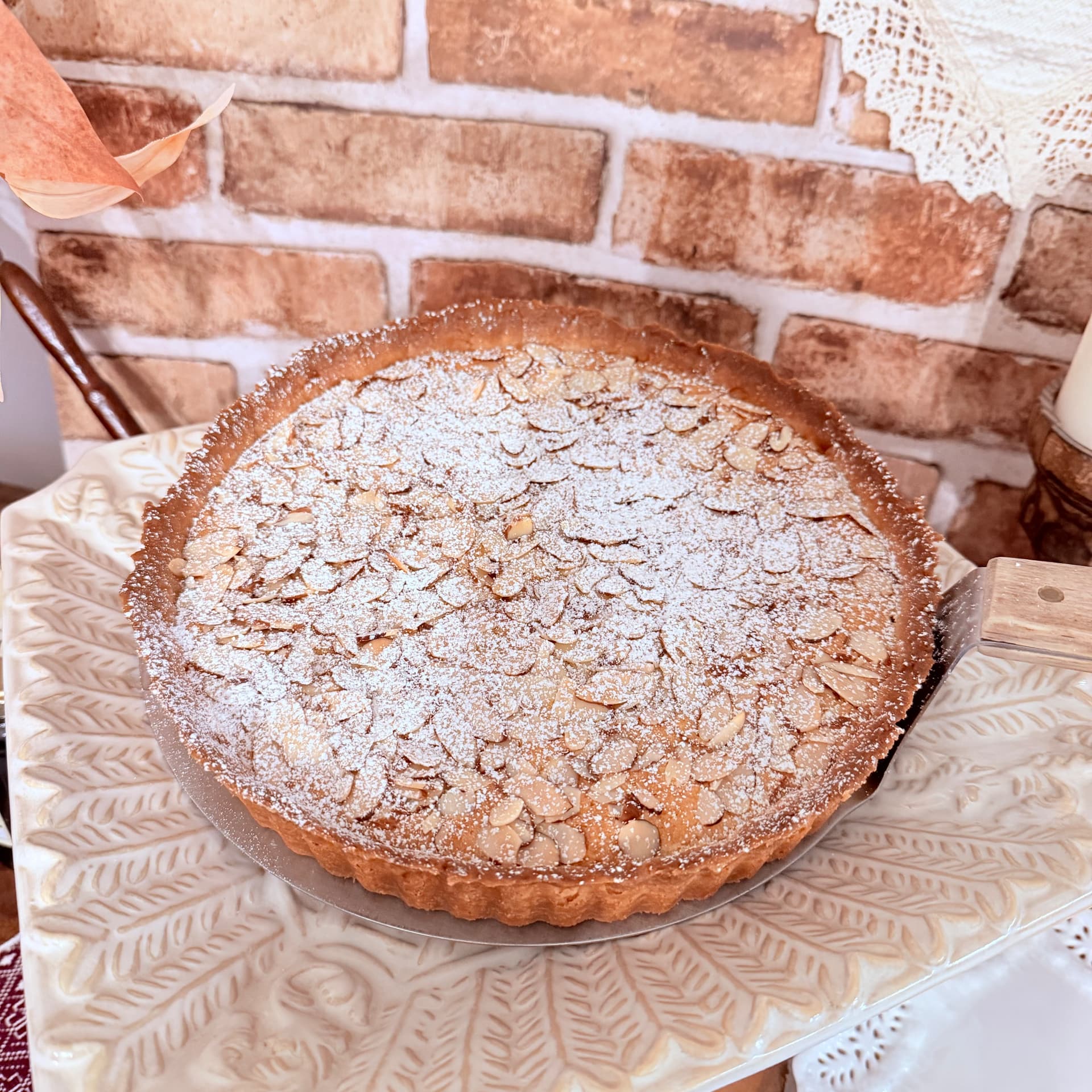 Golden frangipane almond cream tart dusted with powdered sugar and topped with sliced almonds — Frangipane Tart from Mama Rozi's Bakehouse in LaGrange, KY